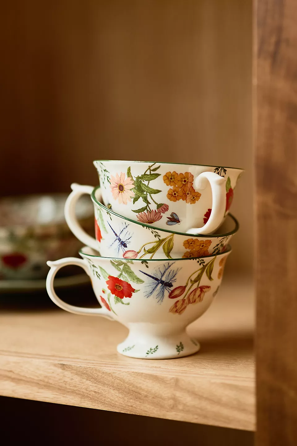 a stack of floral printed tea cups on a cabinet shelf
