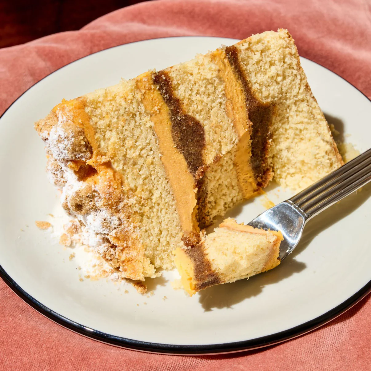 A piece of cake on a plate with a fork holding a small bite