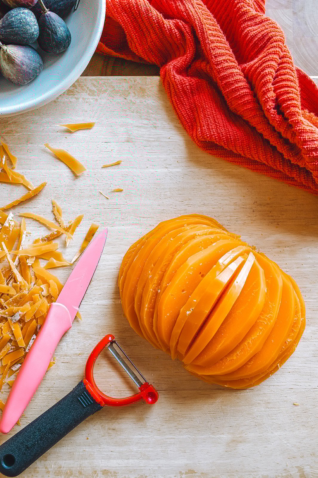 A ball of Mimolette cheese on a cutting board fanned out into slices that resemble the shape of a pumpkin