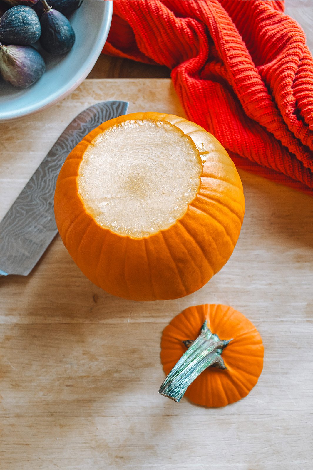 A pumpkin on a cutting board with the stem cut off