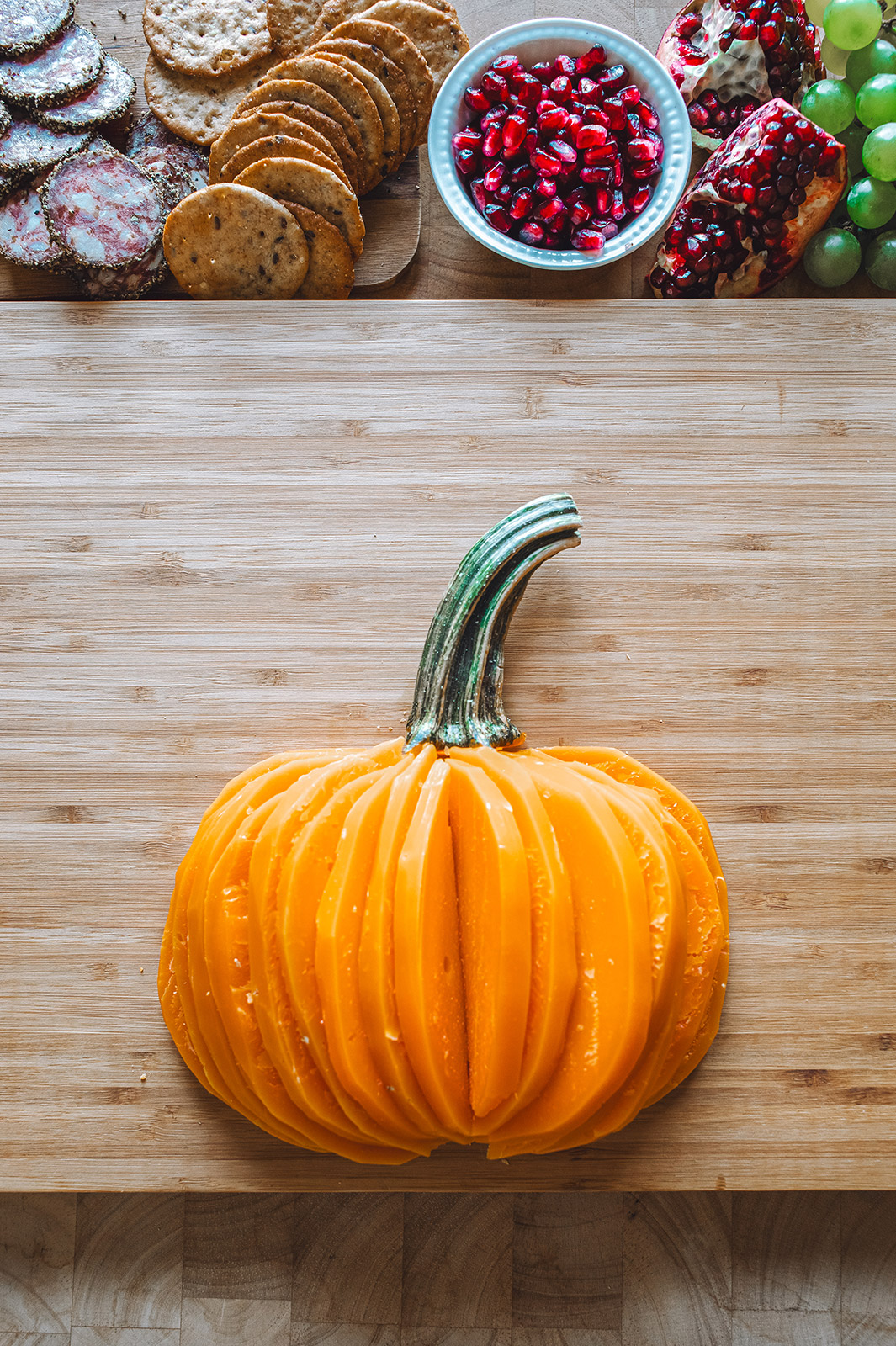 A charcuterie board with Mimolette cheese cut in the shape of a pumpkin