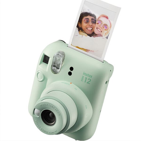 An instant camera printing a photo of two smiling friends who are hugging