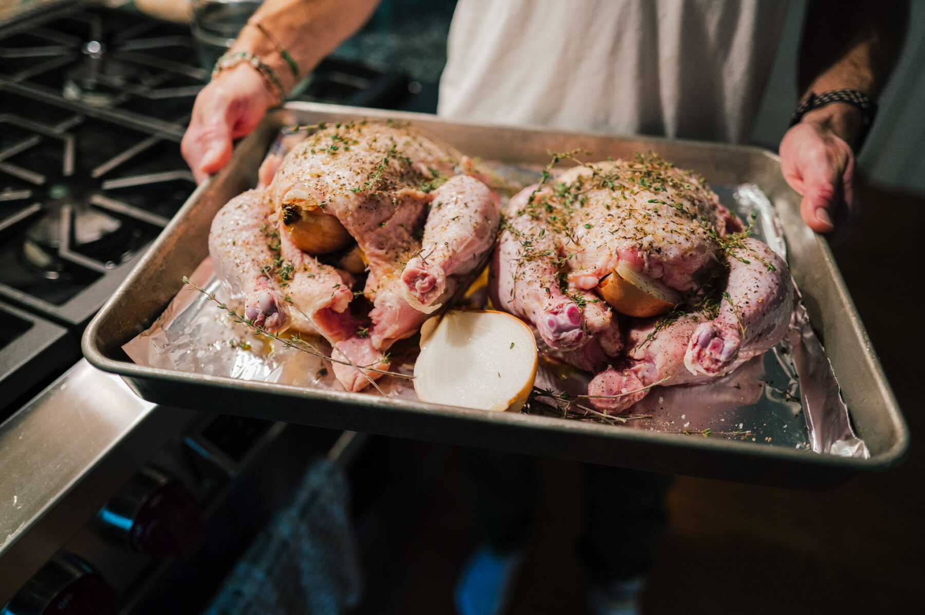 Two herb-seasoned chickens and an onion ready to go into the oven